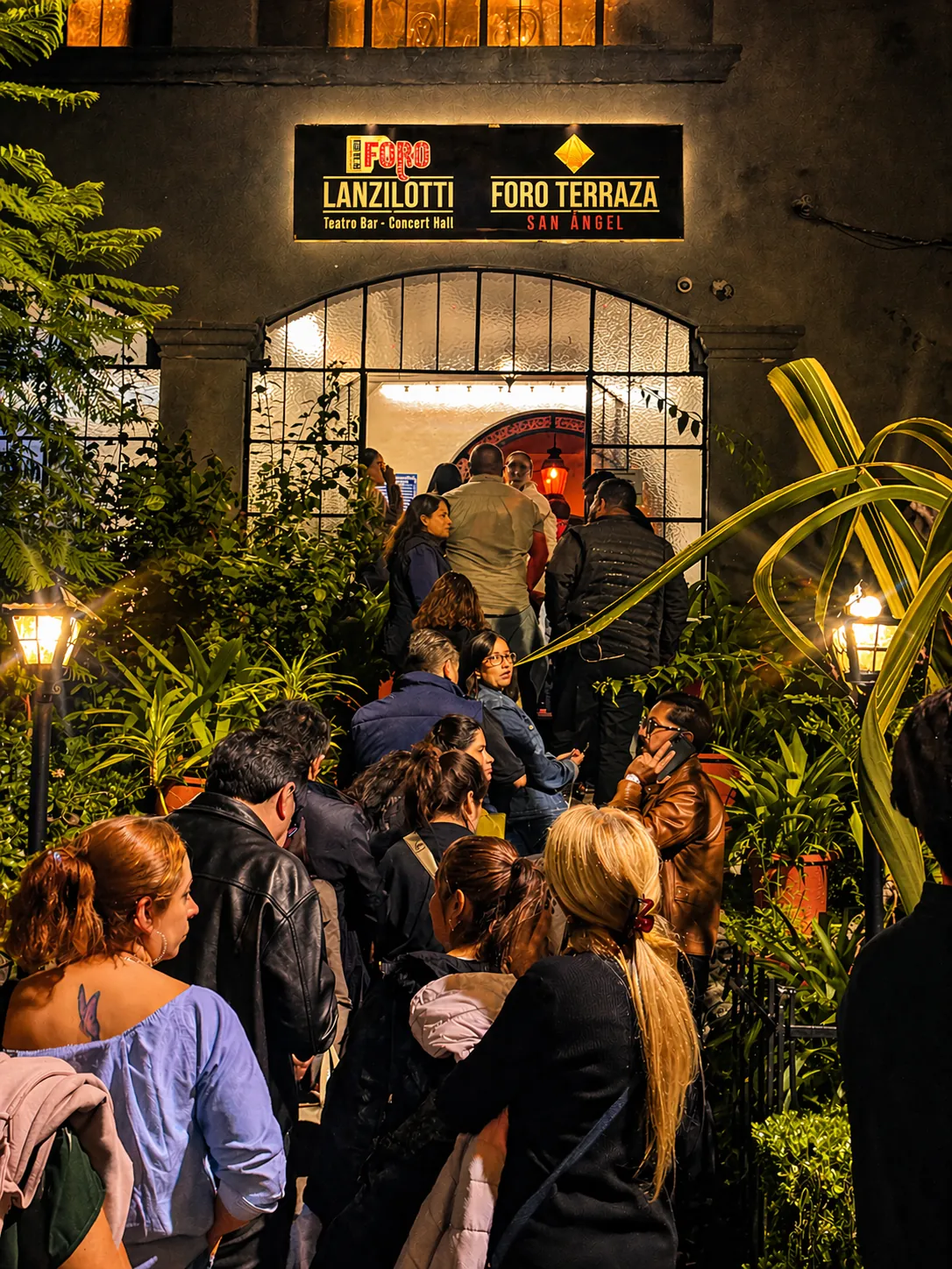 La entrada del recinto de noche, con el público llegando a los foros